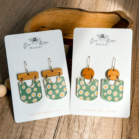 Pair of earrings on display cards with floral design, wooden accents, and 'Bee & Me' branding.