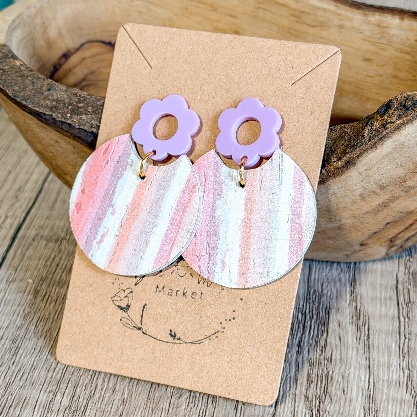 Pair of earrings with floral tops on a 'Market' branded card, set against a wooden background.