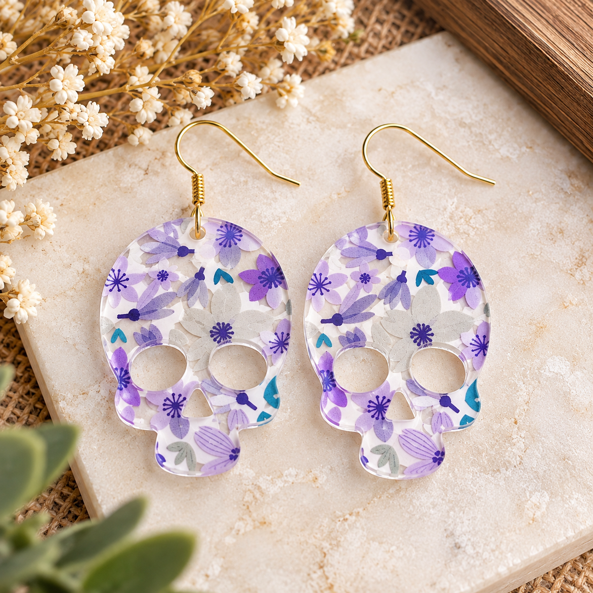 Clear acrylic floral skull earrings in purple and white with gold hooks