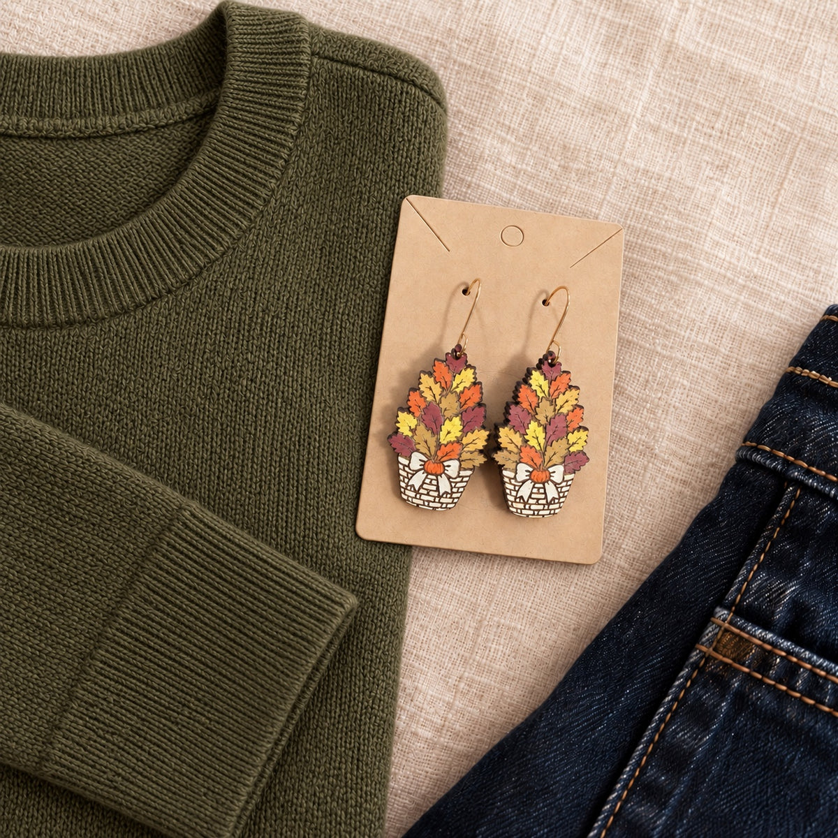 Hand-painted fall basket wood earrings styled with an olive sweater and dark denim