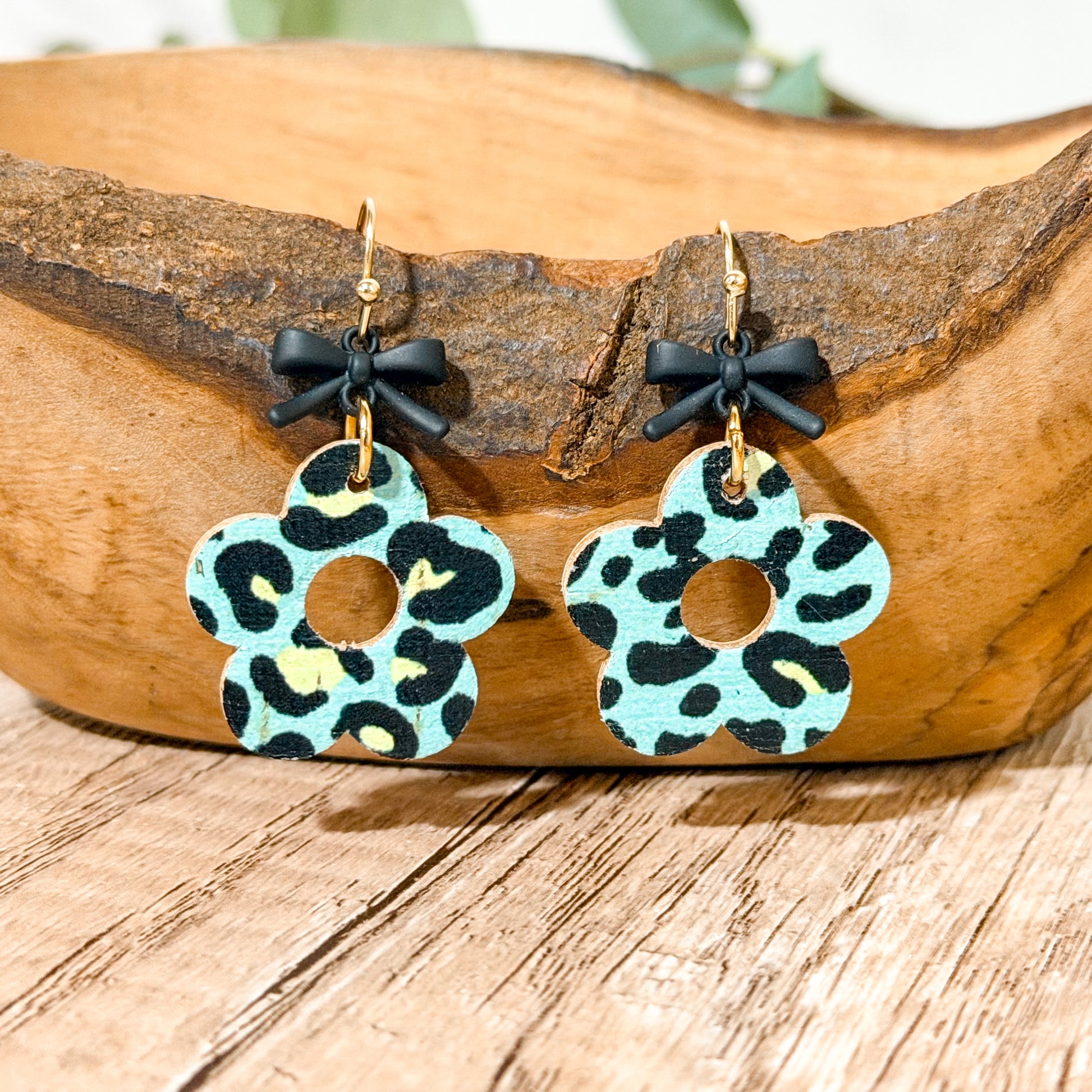 Pair of earrings with leopard print design hanging on a wooden surface