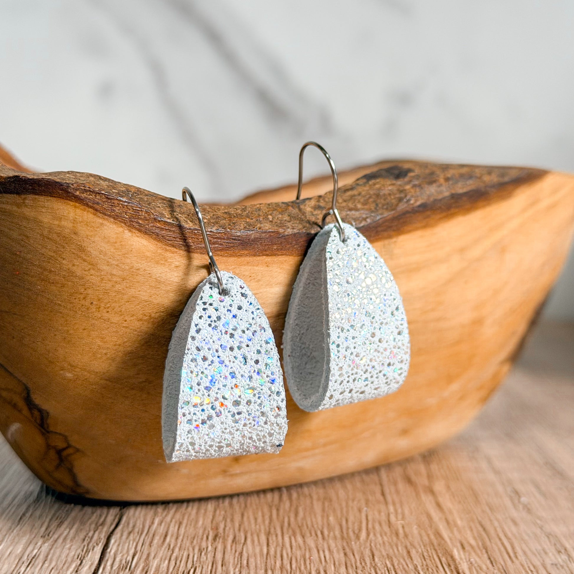 Loop hoop earrings with glittery finish on a wooden surface
