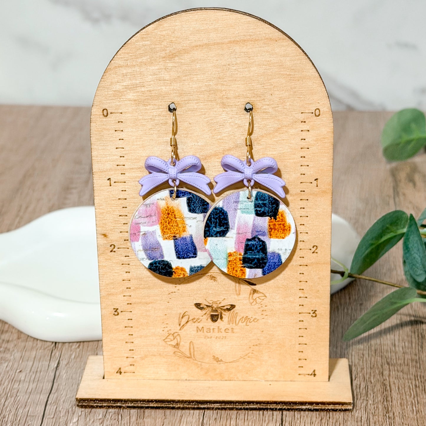 Lavender bow earrings with colorful brushstroke leather circles.