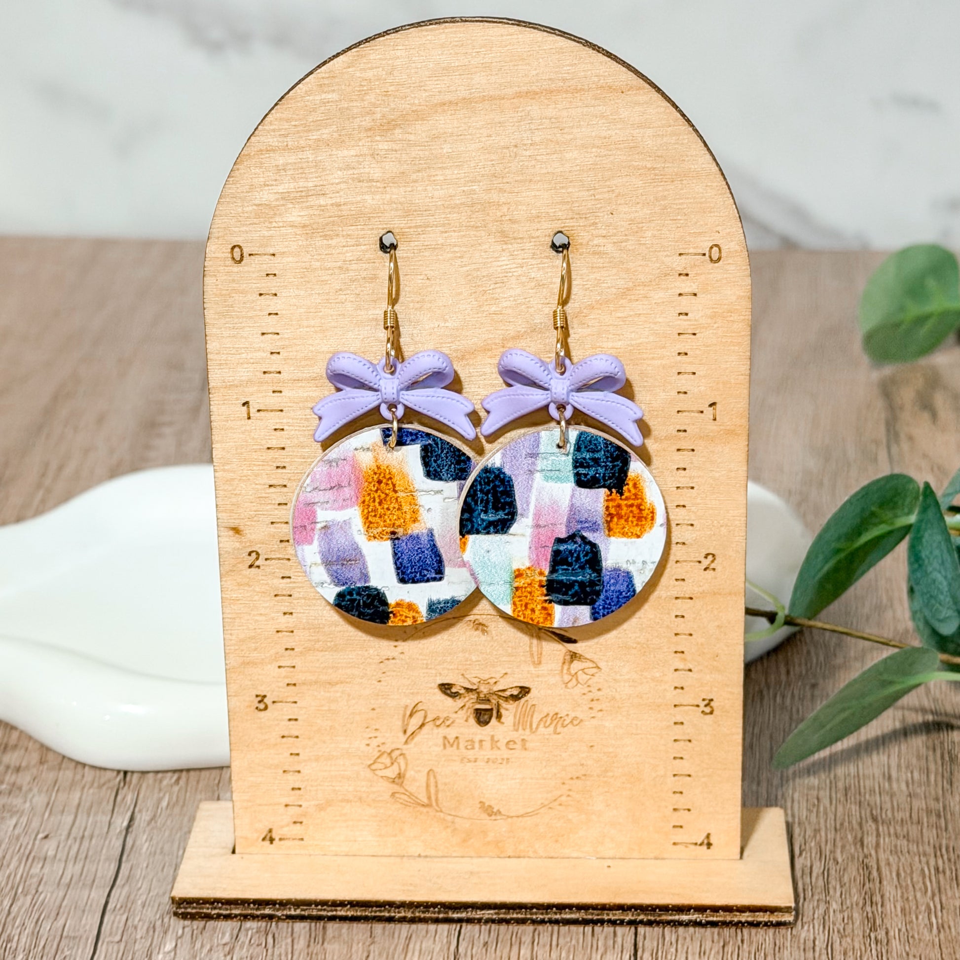 Lavender bow earrings with colorful brushstroke leather circles.