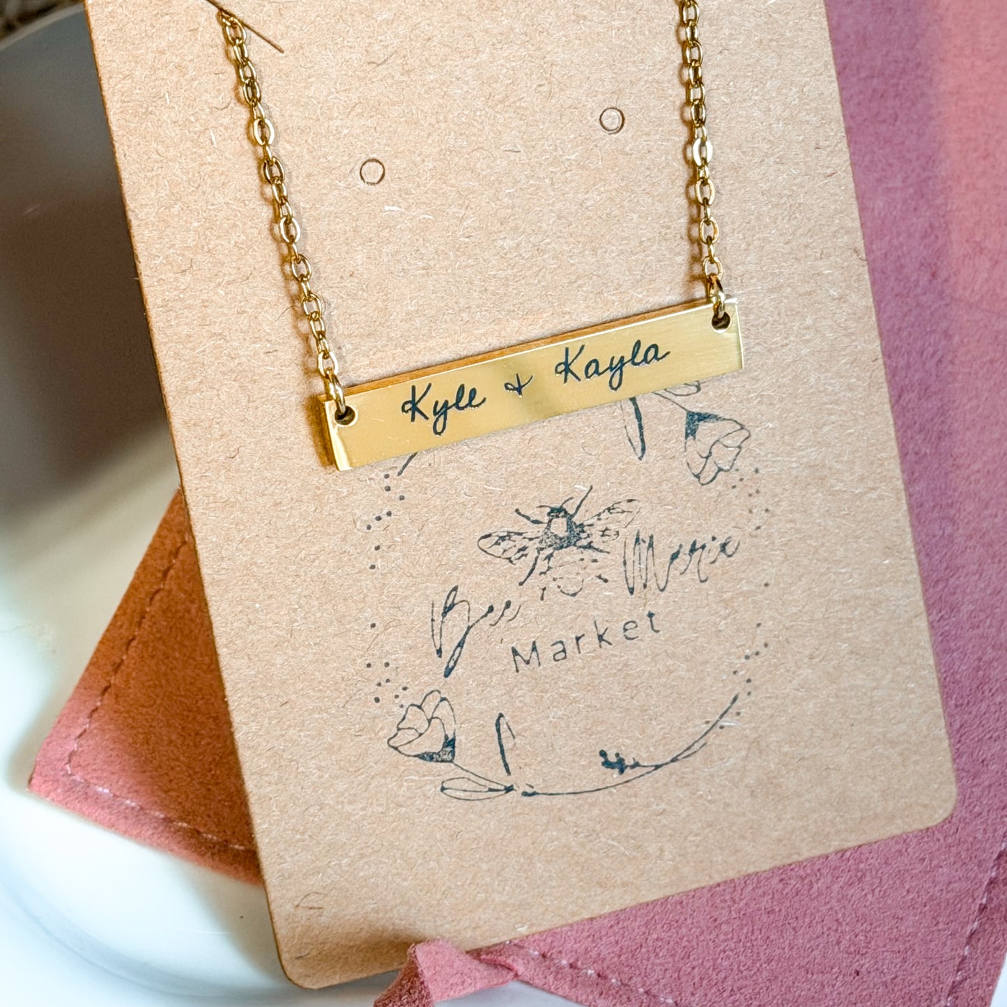 Gold necklace with engraved names on a branded card