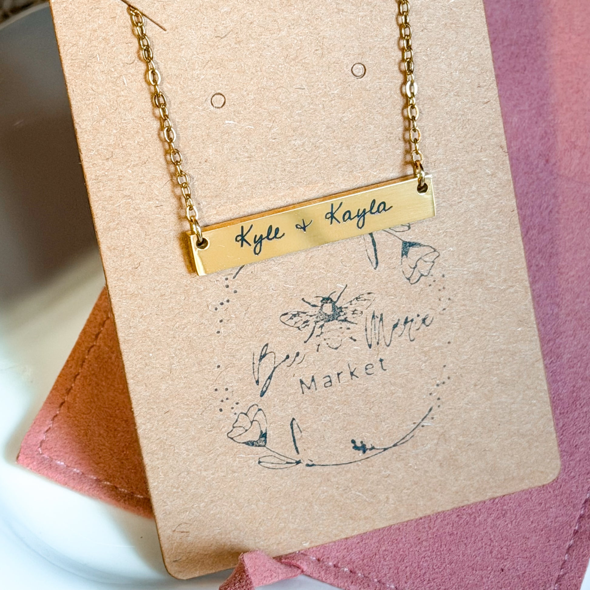 Gold necklace with engraved names on a branded card