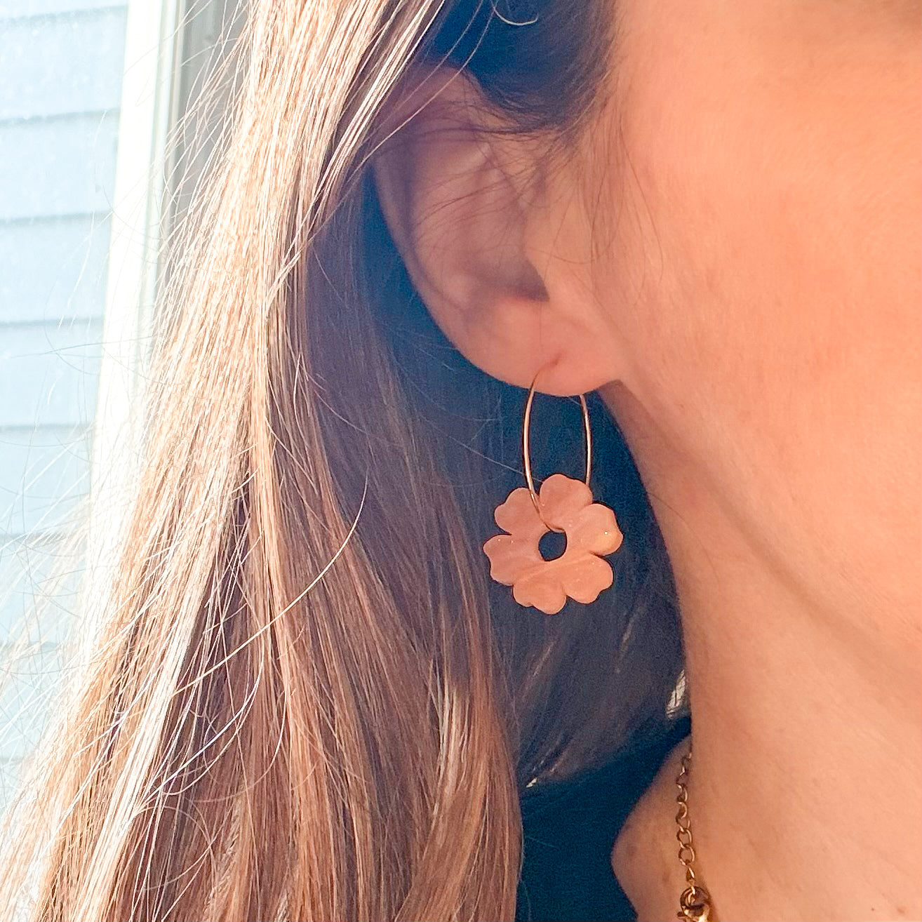 Close-up of a person wearing a floral earring with a blurred background