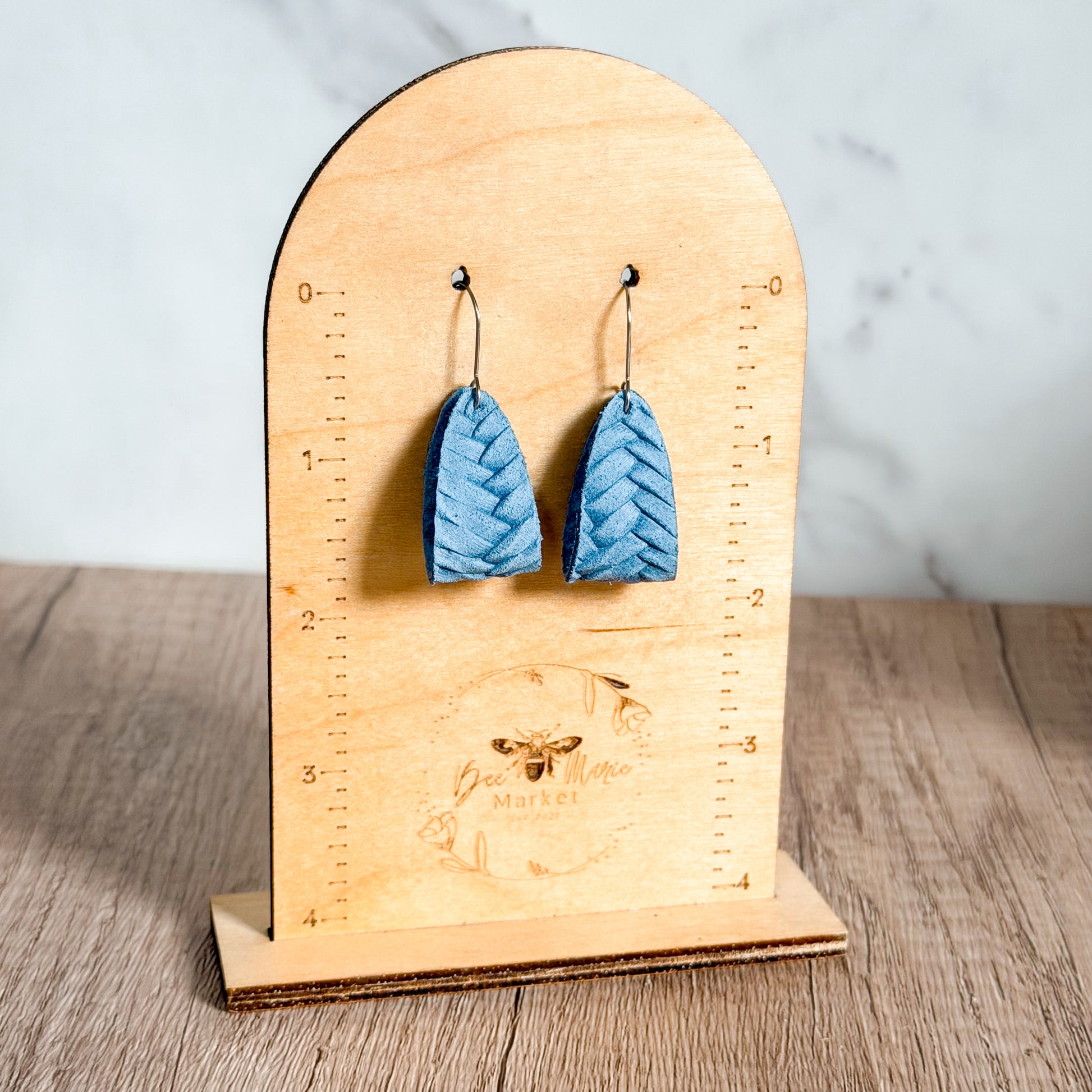 Blue earrings on a wooden stand with measurement markings