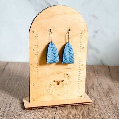 Blue earrings on a wooden stand with measurement markings