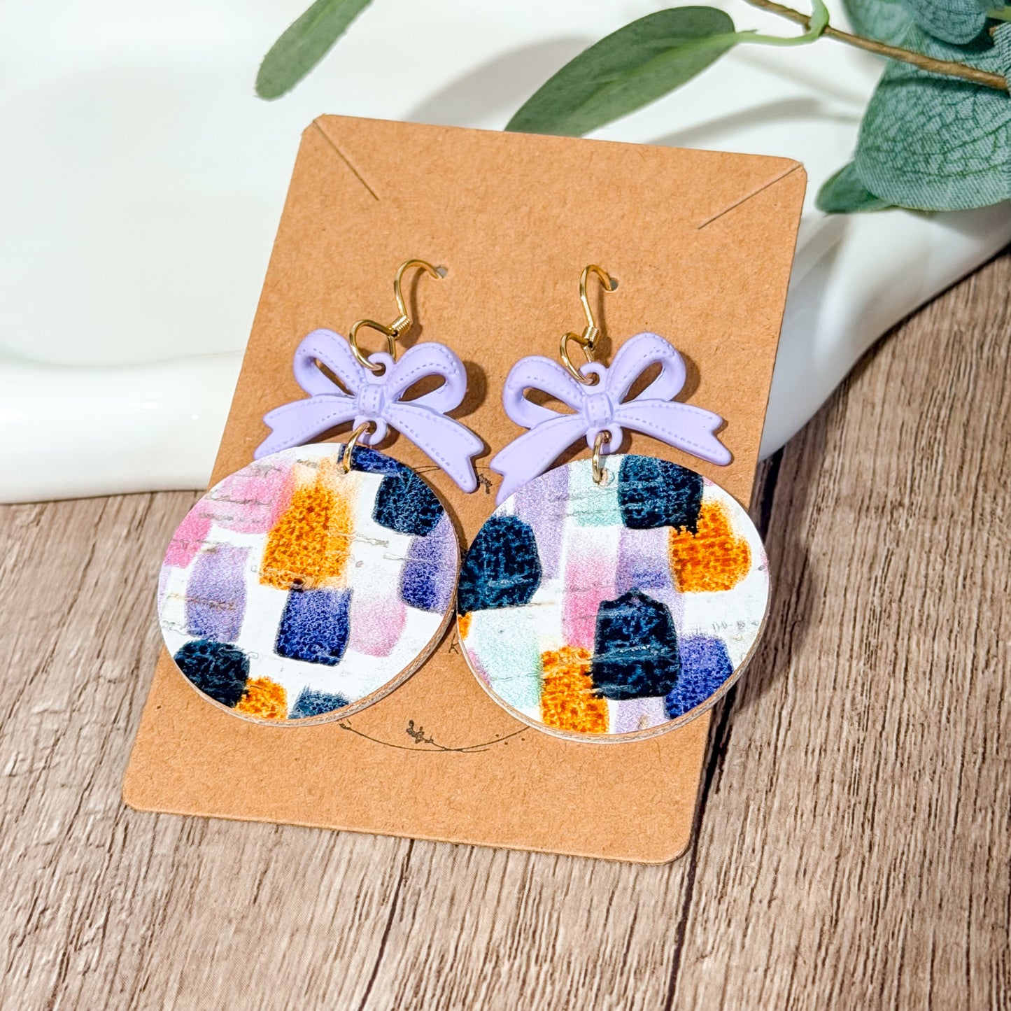 Lavender bow earrings with colorful brushstroke leather circles.