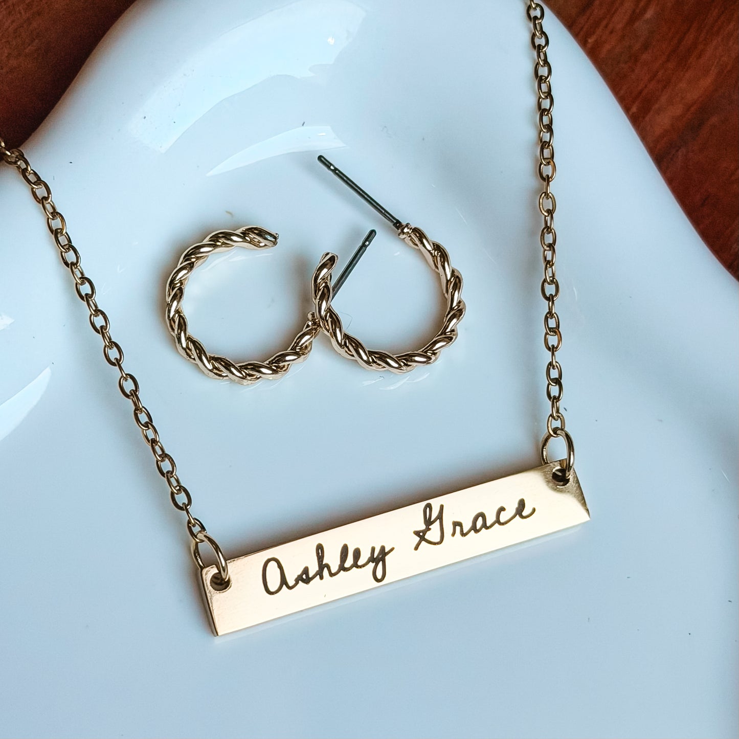 Gold necklace with 'Ashley Grace' engraving on a white dish