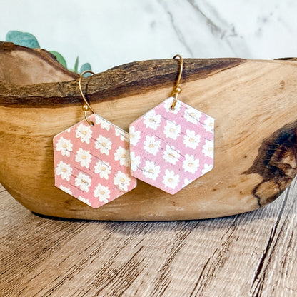 Hexagonal earrings with floral pattern on a wooden surface