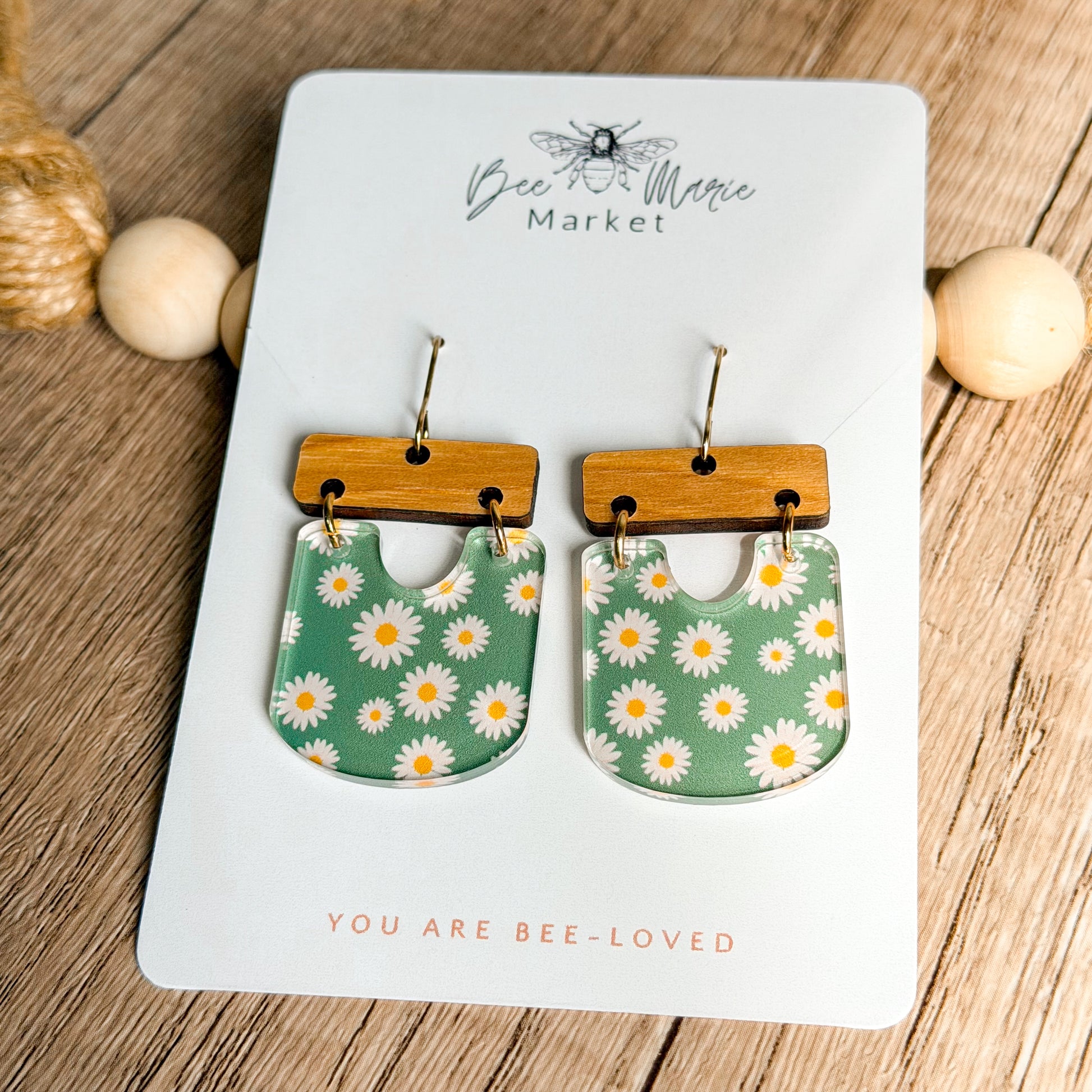 Pair of floral earrings on a 'Bee & Flower Market' card with wooden accents.
