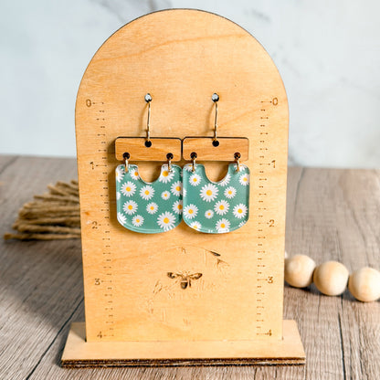 Pair of floral earrings on a wooden stand with a light background
