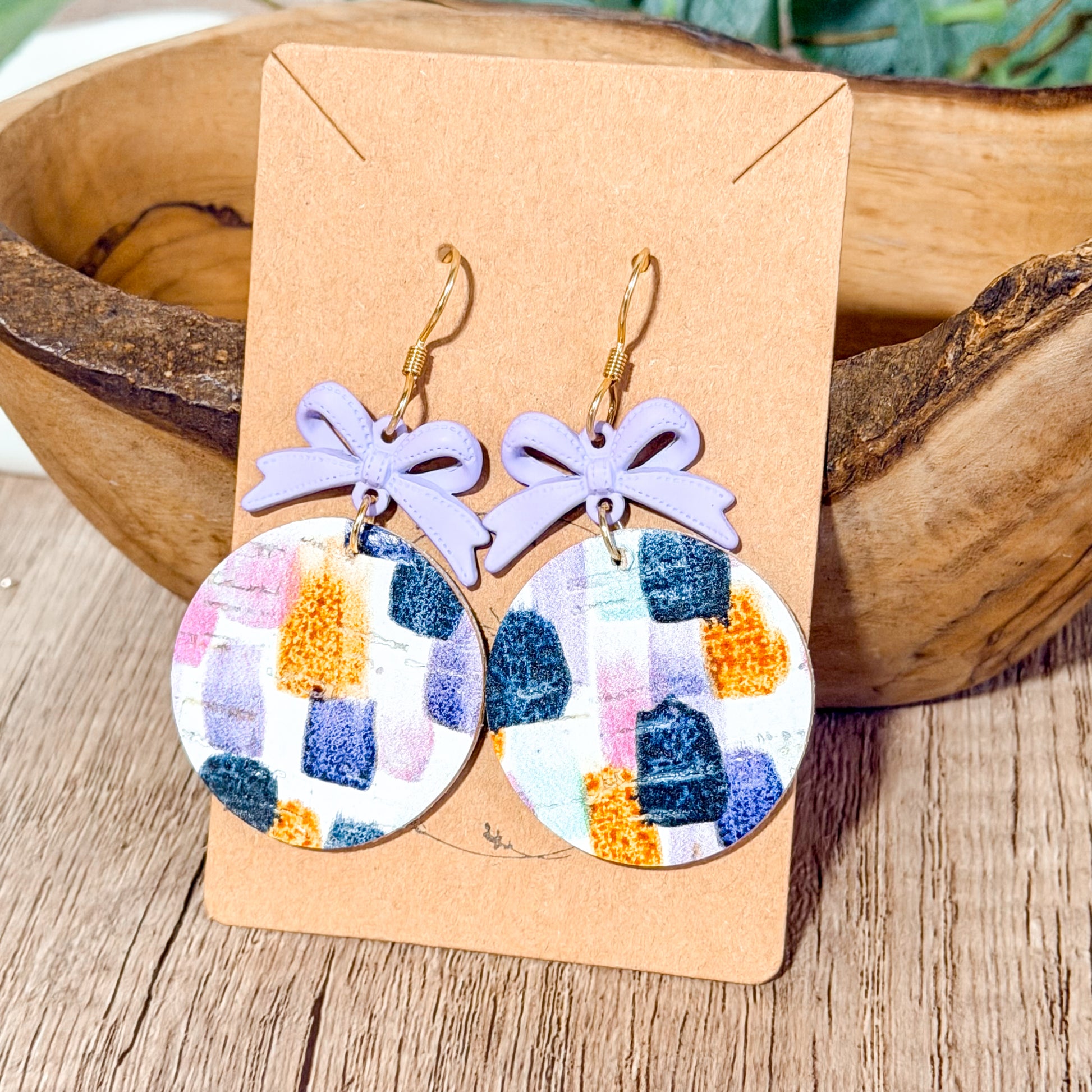 Lavender bow earrings with colorful brushstroke leather circles.