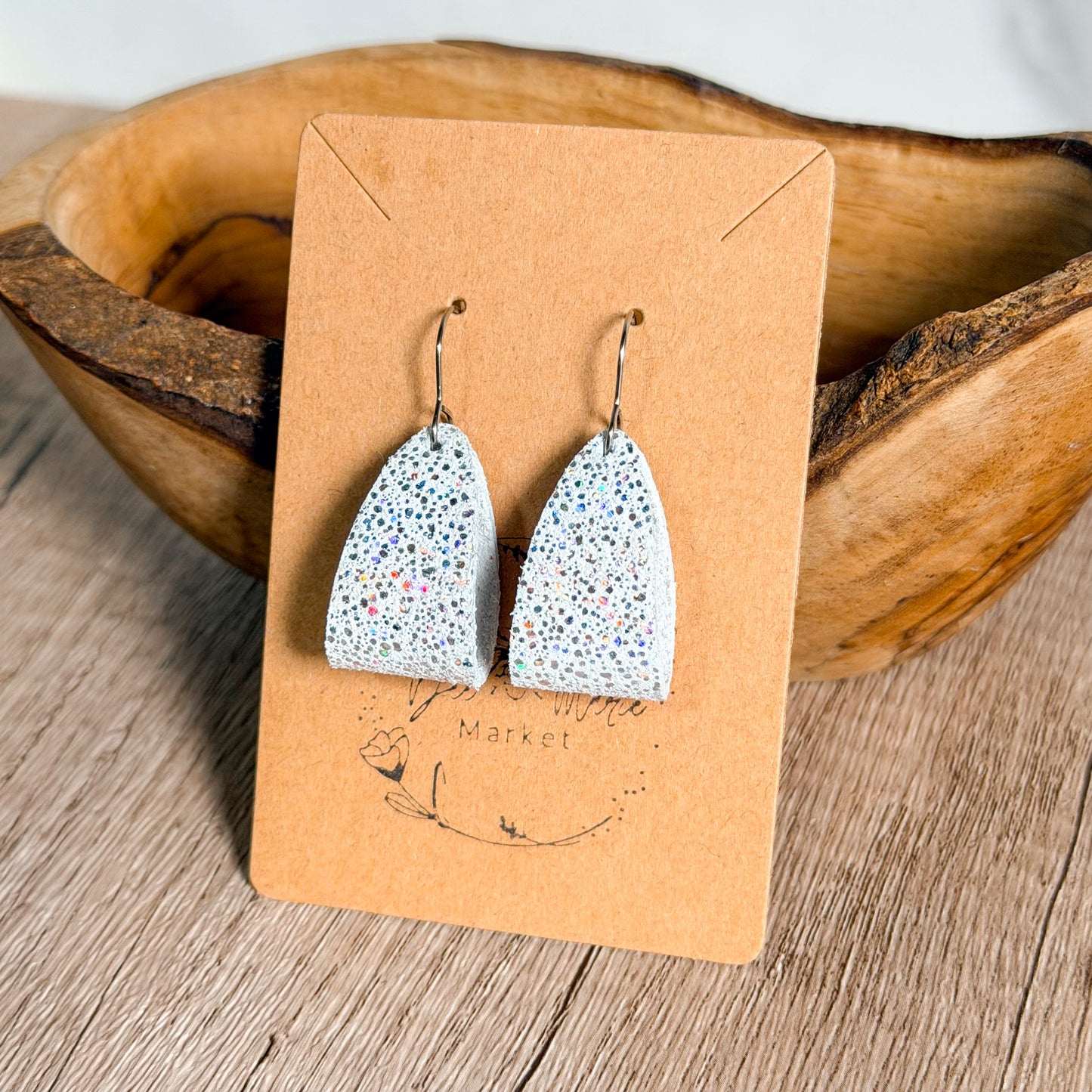 Speckled earrings on a brown card with 'Market' branding, placed in a wooden bowl.