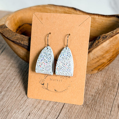 Speckled earrings on a brown card with 'Market' branding, placed in a wooden bowl.