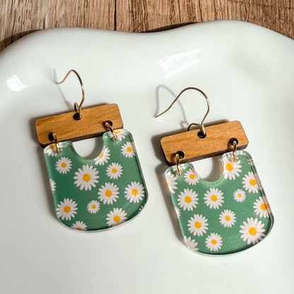 Floral patterned earrings with wooden accents on a white dish.