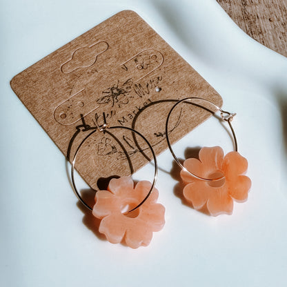 Floral earrings with pink flowers on a brown earring card.