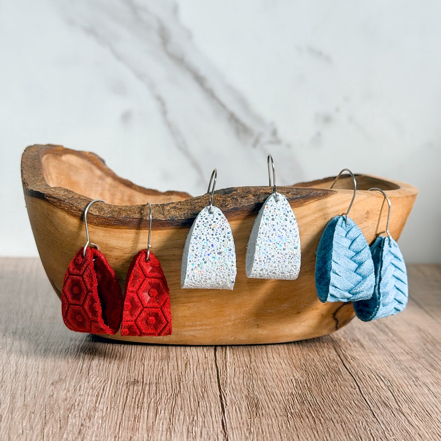 Wooden bowl with red and white earrings on a wooden surface