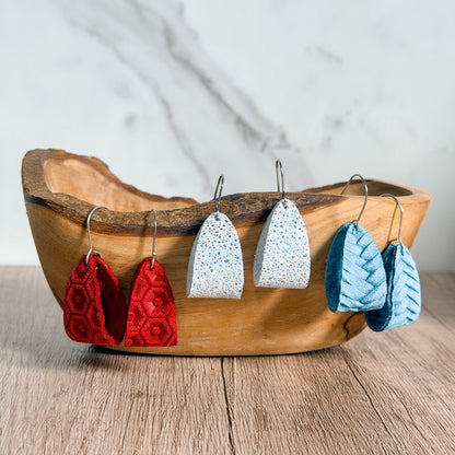 Wooden bowl with red and white earrings on a wooden surface