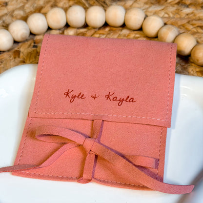 Pink fabric pouch with 'Kyle & Kayla' engraved on a woven surface.