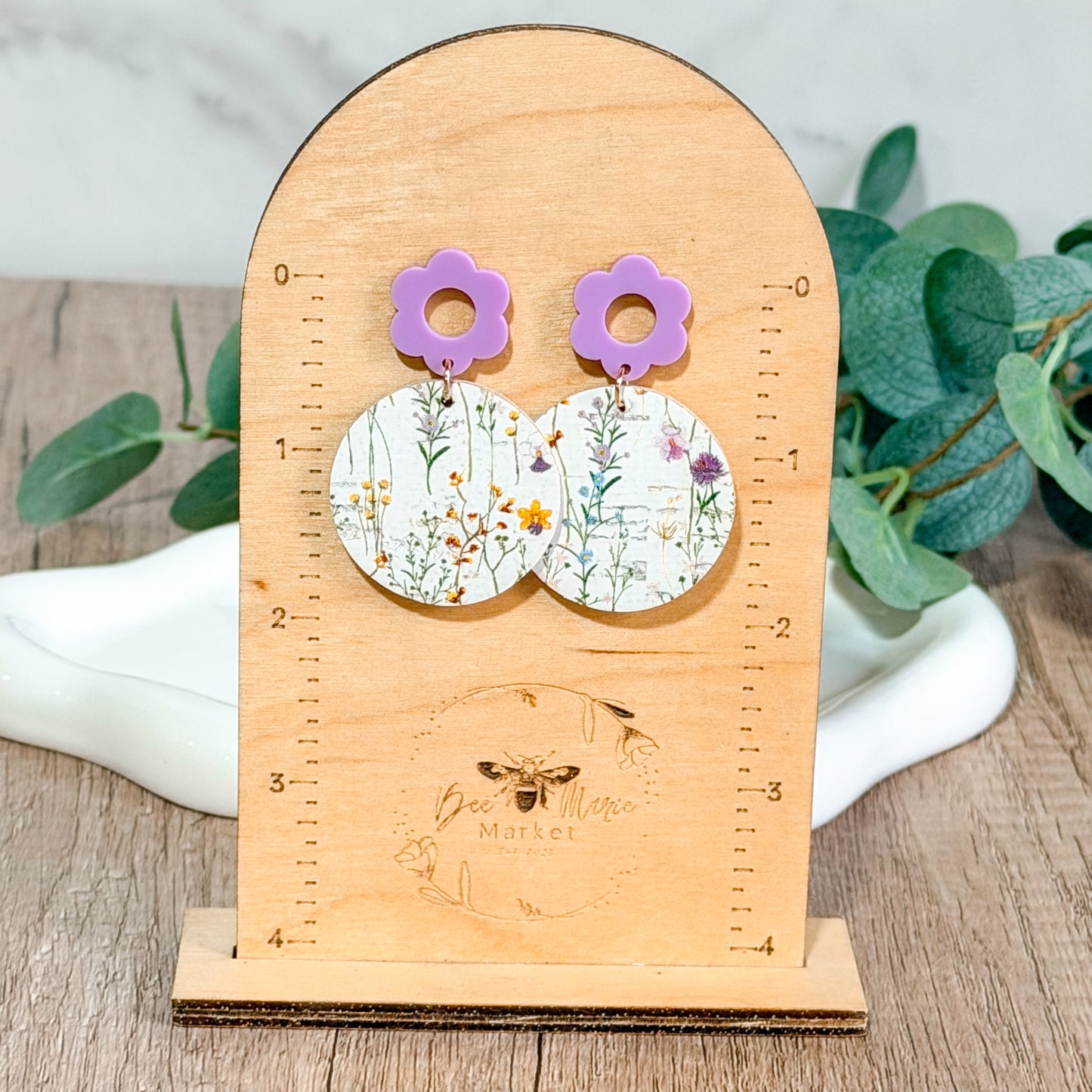 Lavender flower top wildflower print earrings displayed on a wooden Bee Marie Market earring stand for size reference.