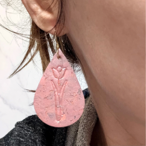 Close-up of a pink textured earring worn by a person.