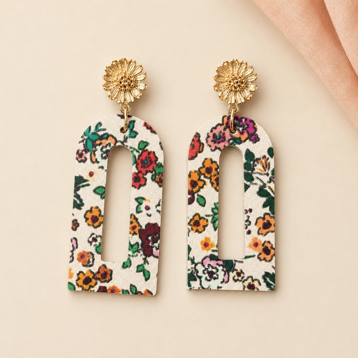 Cream floral arch earrings with gold flower studs on a warm cream background.