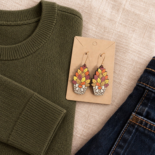 Hand-painted fall basket wood earrings styled with an olive sweater and dark denim