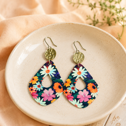 Colorful floral teardrop earrings styled in a cream dish with peach fabric.