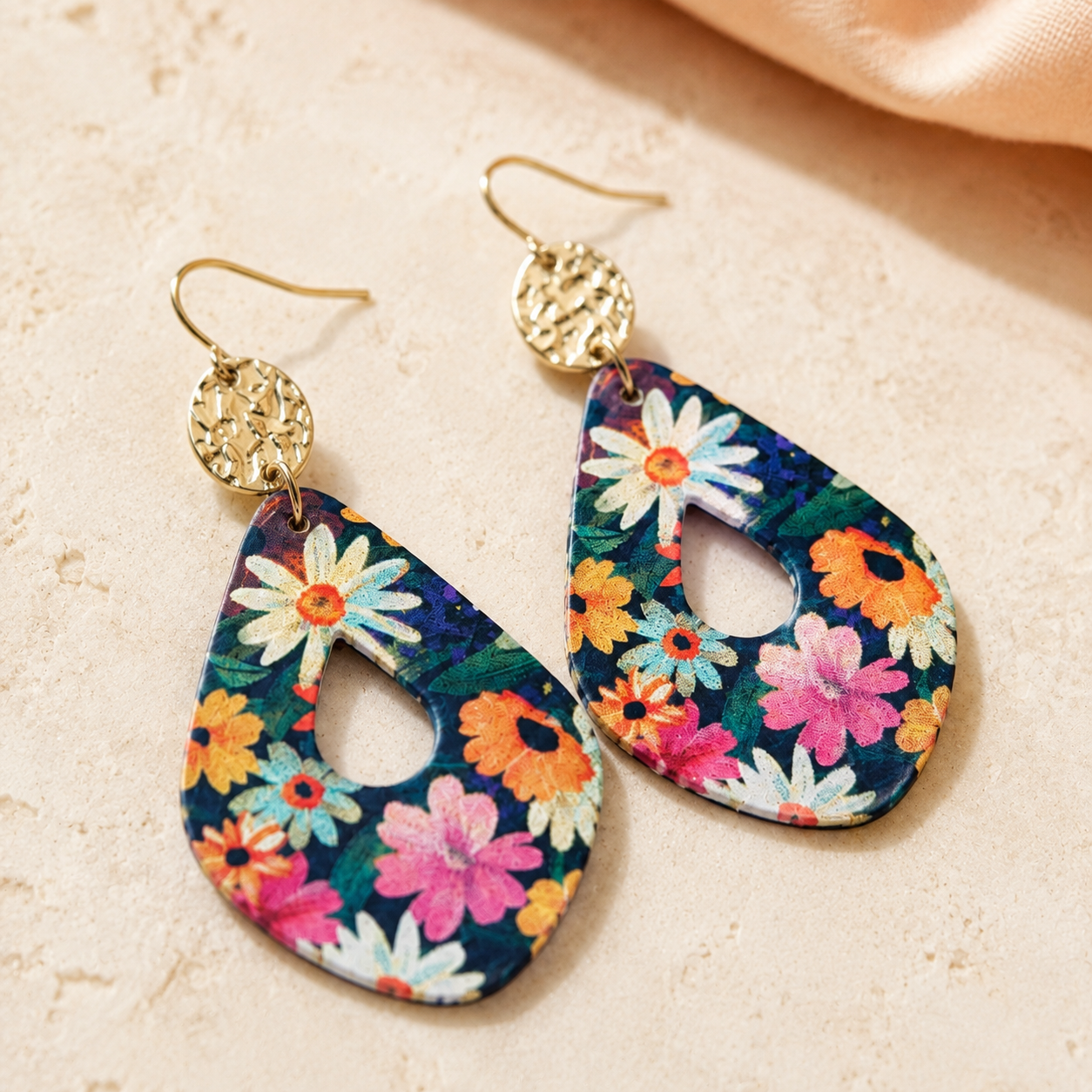 Close-up of navy floral teardrop earrings with hammered gold accents.