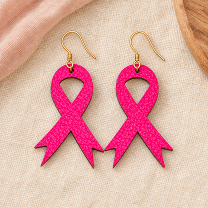 Hot pink awareness ribbon earrings with gold hooks on an ivory boutique background.
