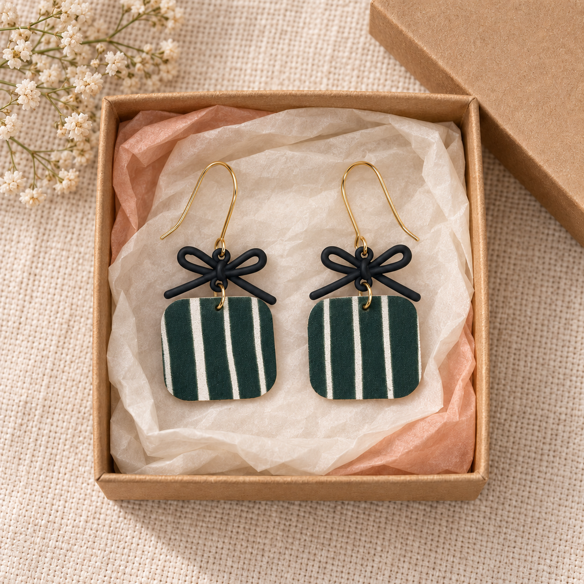 Hunter green striped bow earrings styled inside a kraft gift box.