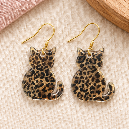 Leopard-print acrylic cat earrings with gold hook loops threaded through the top holes
