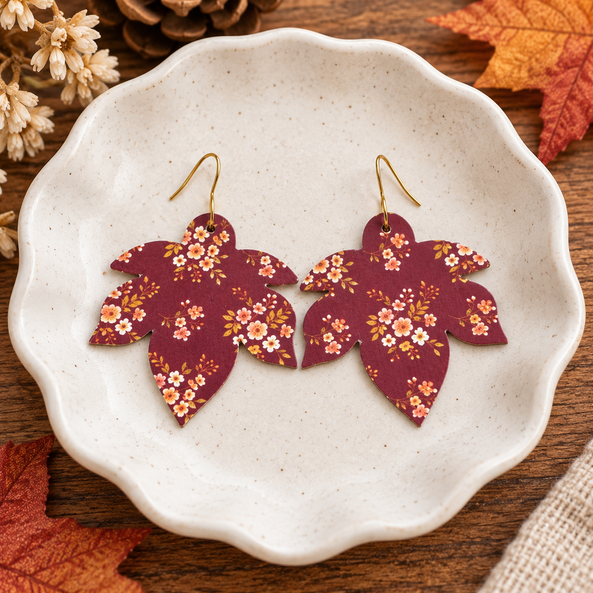 Maroon floral maple leaf earrings on an autumn dish