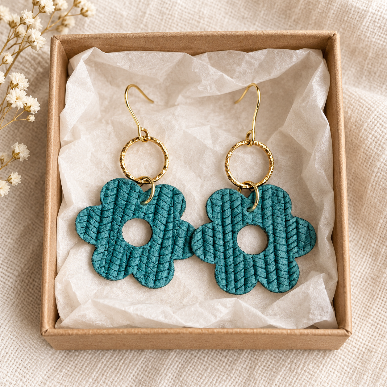 Medium teal leather flower earrings arranged in a kraft gift box
