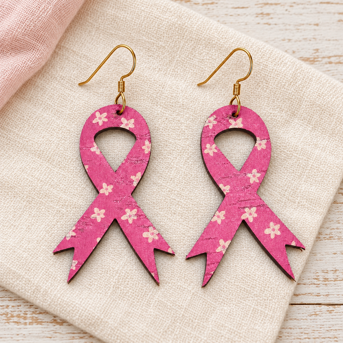 Pink floral awareness ribbon earrings with gold hooks on ivory linen.