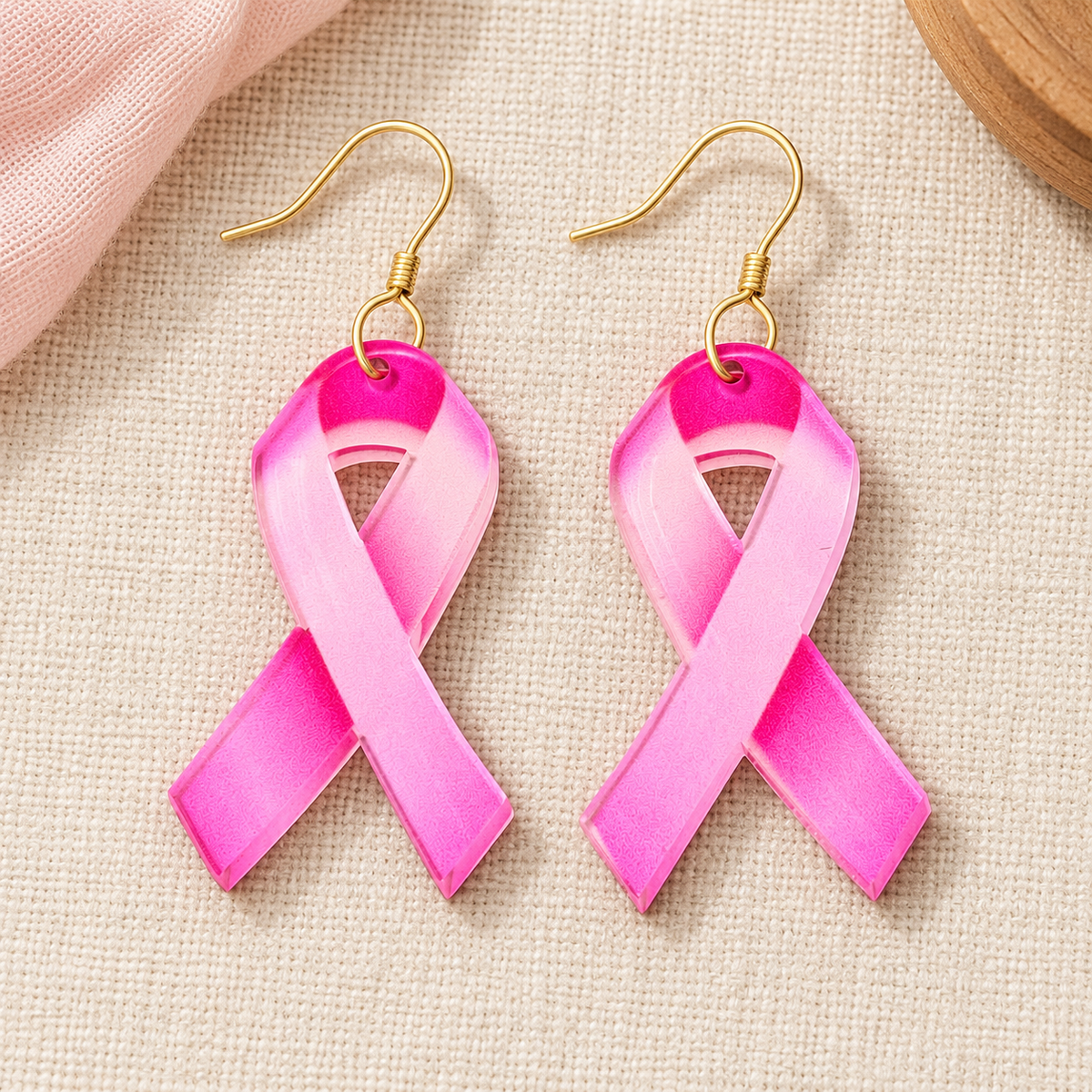 Pink ombré acrylic awareness ribbon earrings with gold stainless steel hooks on ivory linen.