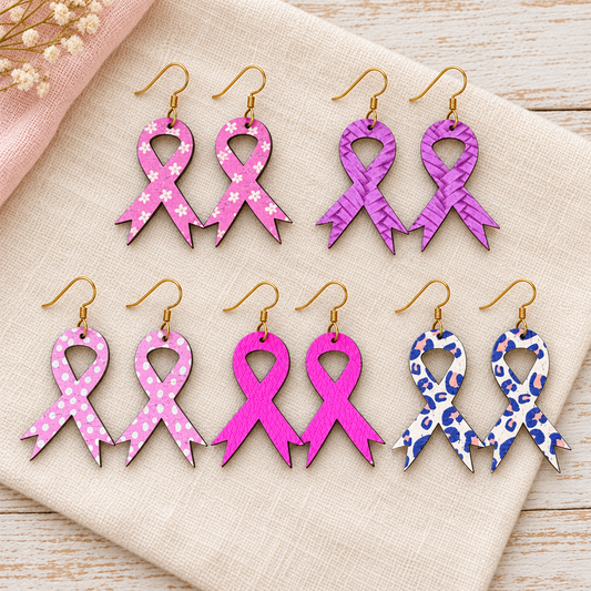 Five pairs of handmade pink ribbon earrings with gold hooks on ivory fabric.