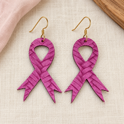 Purple textured awareness ribbon earrings with gold hooks on ivory fabric.