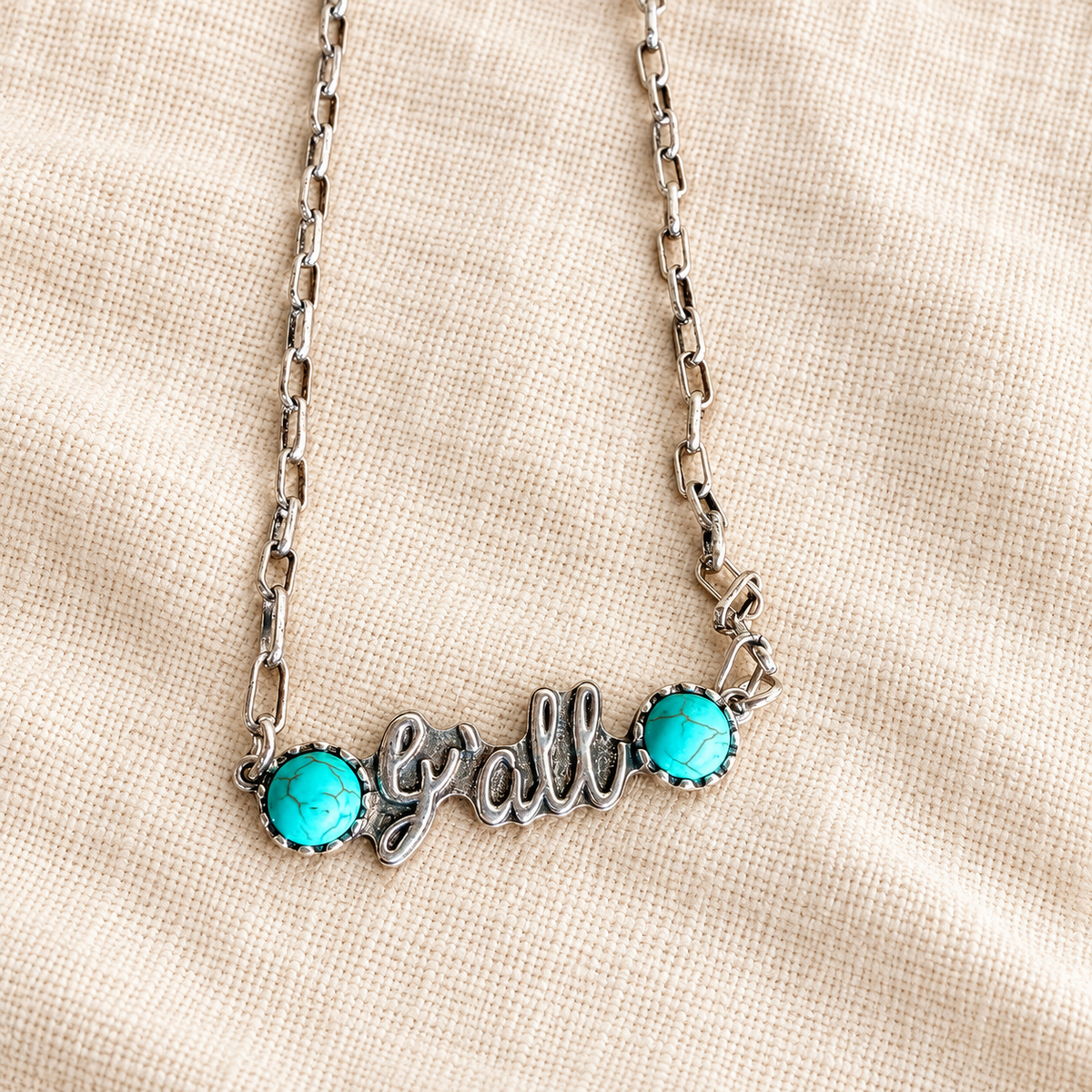 Close view of silver y'all necklace centerpiece and turquoise accents
