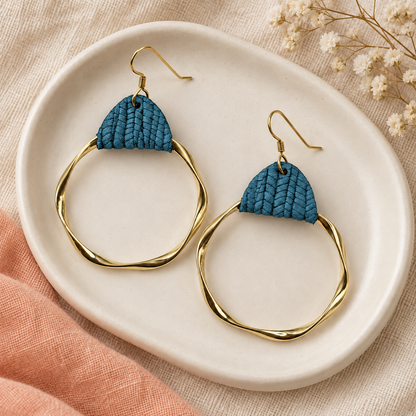 Teal textured leather earrings with oversized twisted gold hoops on a cream dish.