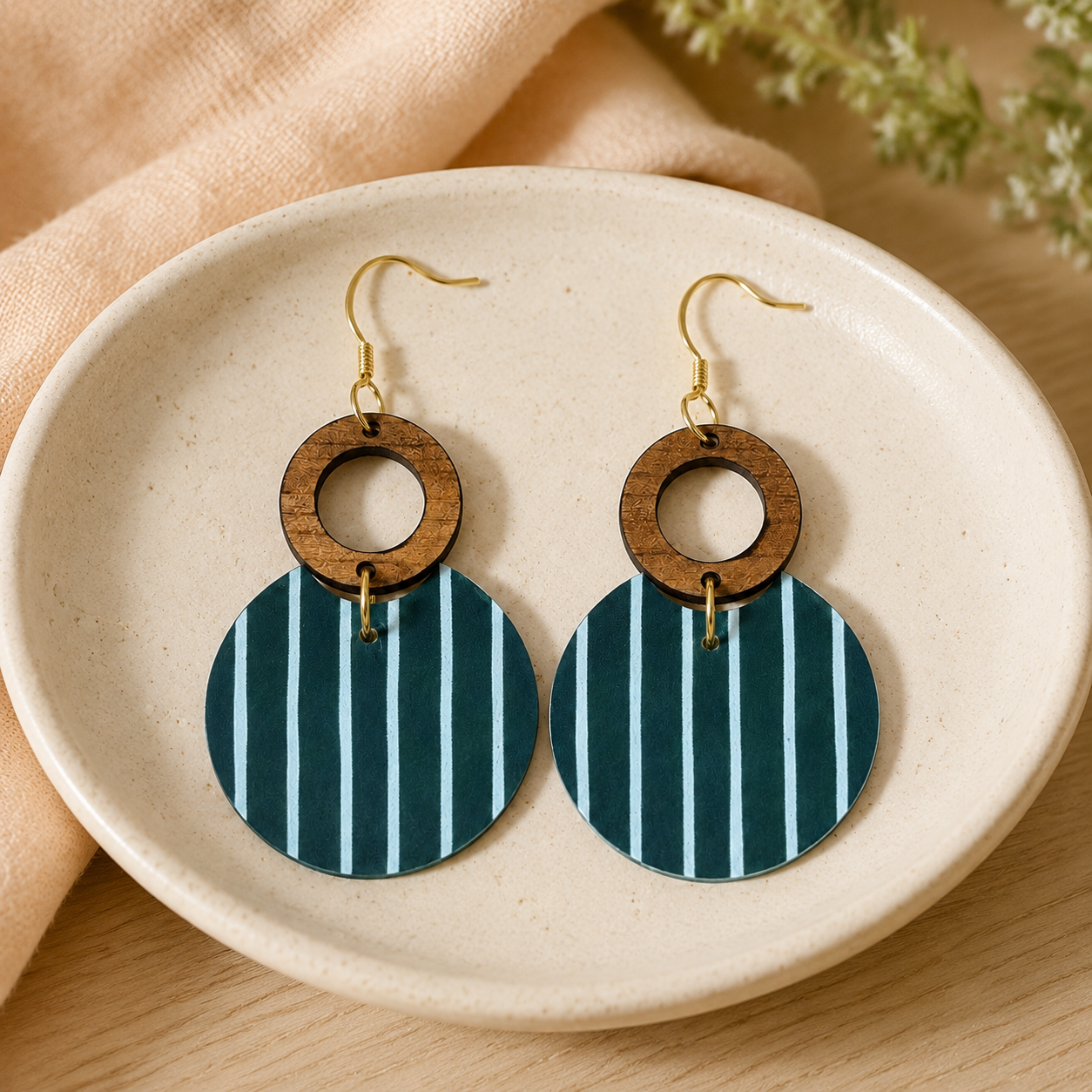 Teal striped wood circle earrings styled in a cream ceramic dish.