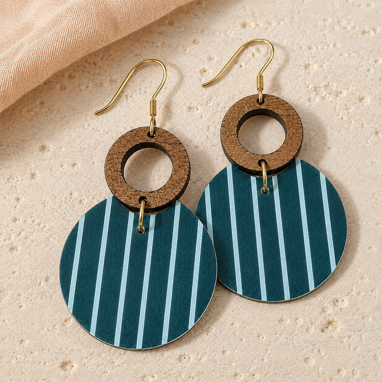 Close-up of teal striped circle earrings with wood grain and gold hardware.
