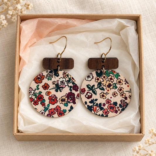 Round floral cork on leather earrings with wood bars and stainless steel hooks in a cream tissue-lined gift box.